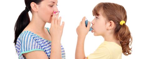 Dame fumant une cigarette et jeune fille utilisant un inhalateur à côté d'elle
